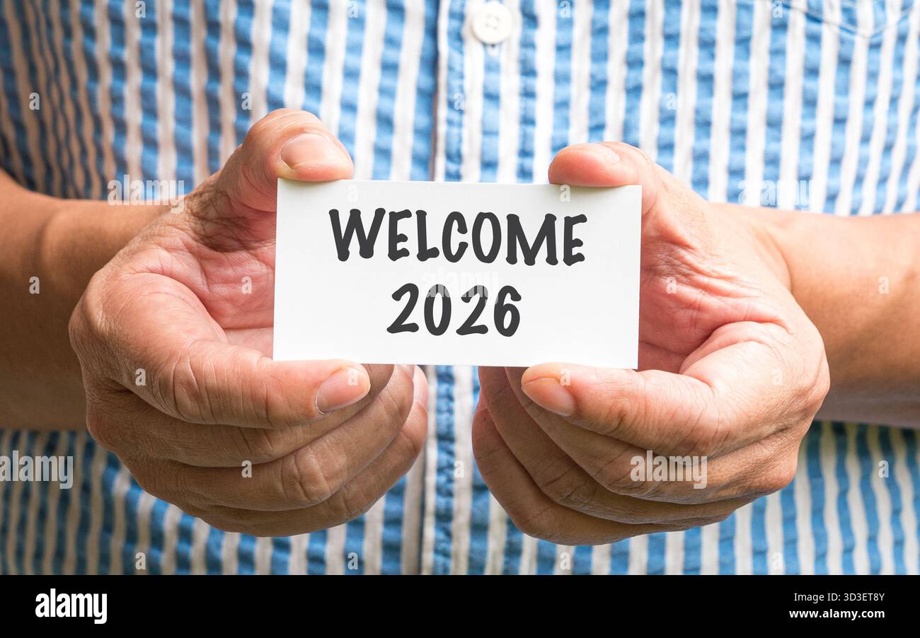 Gros plan d'un homme tenant une carte blanche avec Welcome 2026 Banque D'Images