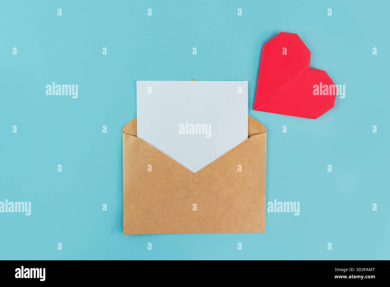 Une enveloppe avec une feuille blanche pour l'écriture et un coeur origami sur fond bleu, un endroit pour le texte Banque D'Images