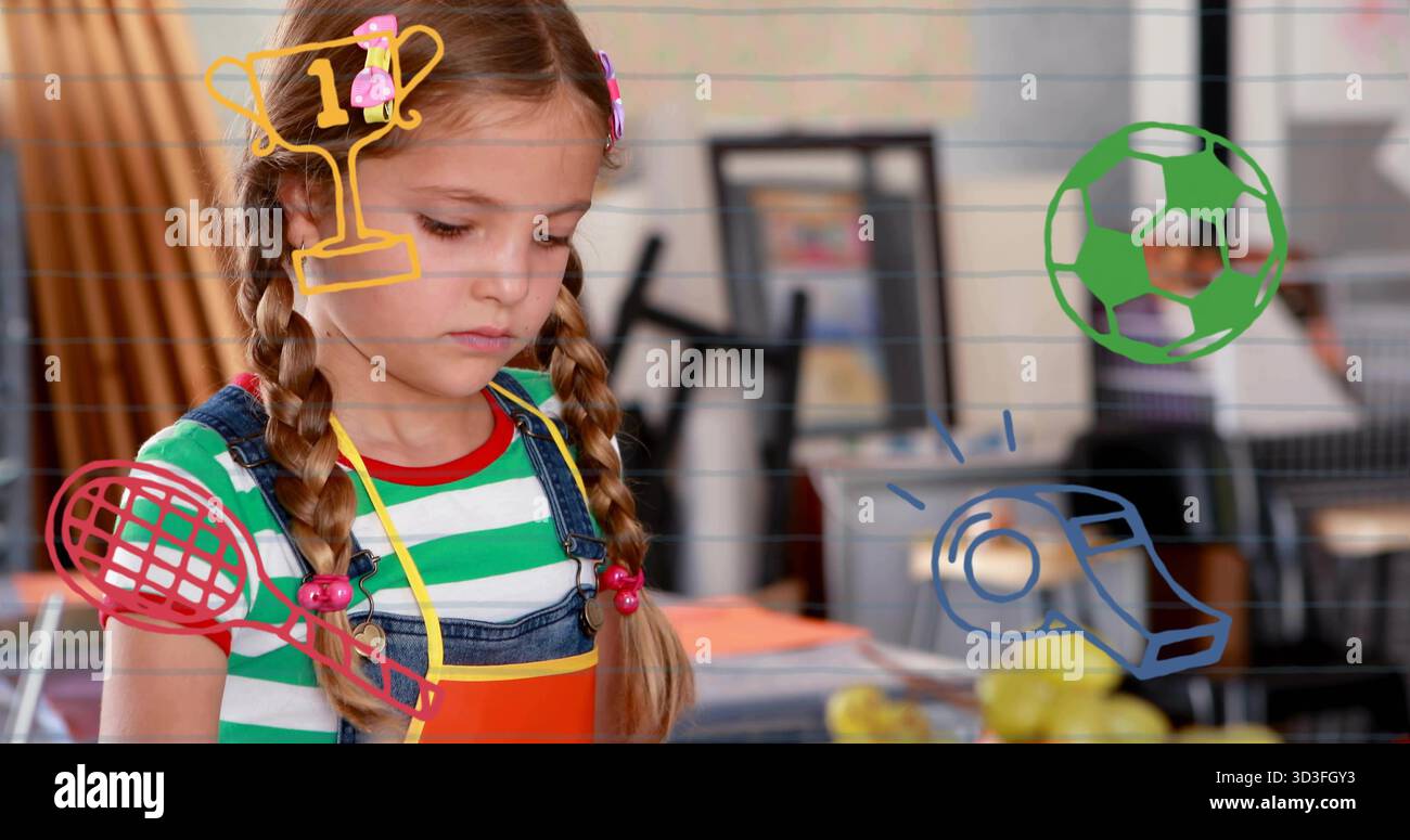 Coupant formes écolière en salopette et tablier travaillant à table dans la salle d'art, avec des griffonnages sportifs Banque D'Images