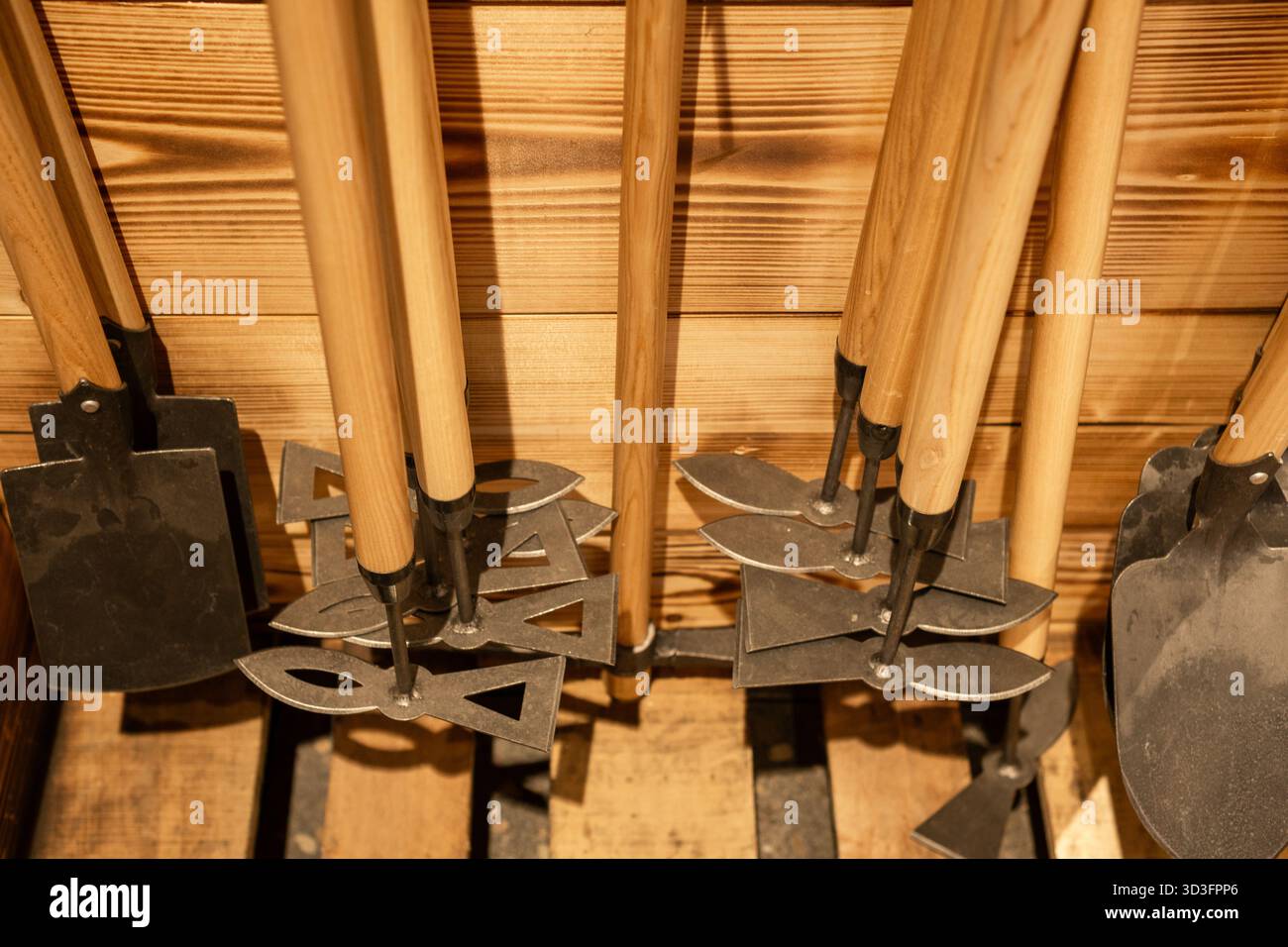 Ensemble de différents outils de jardin avec des poignées en bois disposées sur fond de mur en bois dans l'atelier ou le magasin. Banque D'Images
