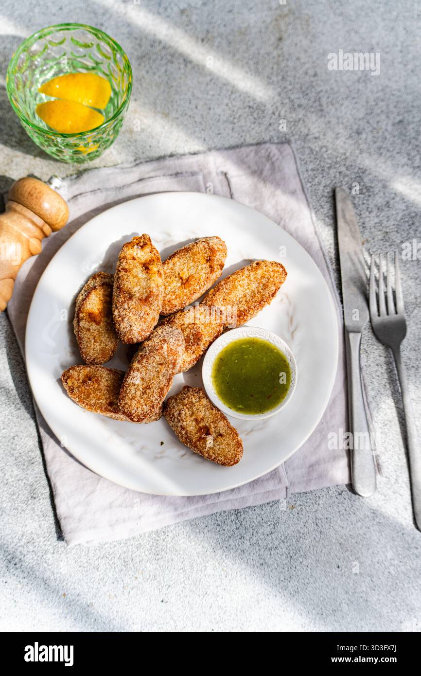 Morceaux de poulet frits croustillants servis sur une assiette blanche avec un accompagnement de sauce aux prunes, accompagnés d'une boisson au citron. Une combinaison parfaite de sucré et salé Banque D'Images