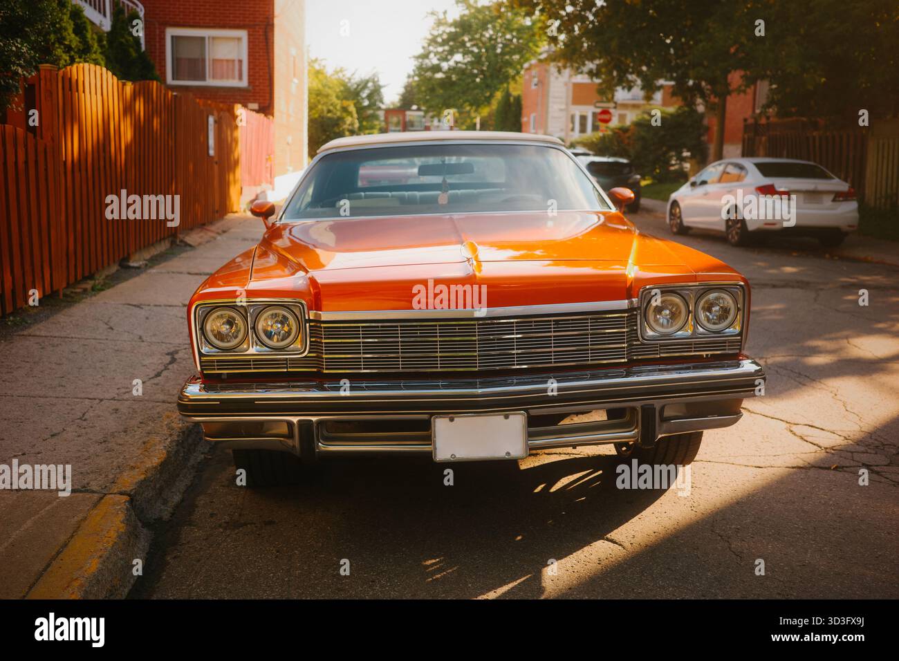 Une superbe voiture cabriolet classique orange est garée dans une charmante rue urbaine. Le véhicule vintage se distingue par sa finition polie, capturant le Banque D'Images