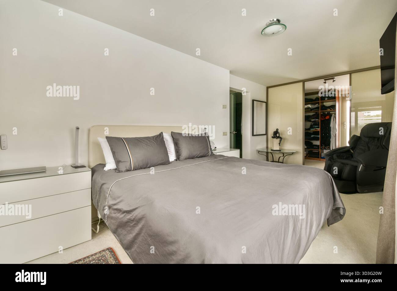 Une chambre élégante avec un lit soigneusement fait, des œuvres d'art décoratives sur les murs et un design de placard contemporain, créant une atmosphère propre et accueillante Banque D'Images
