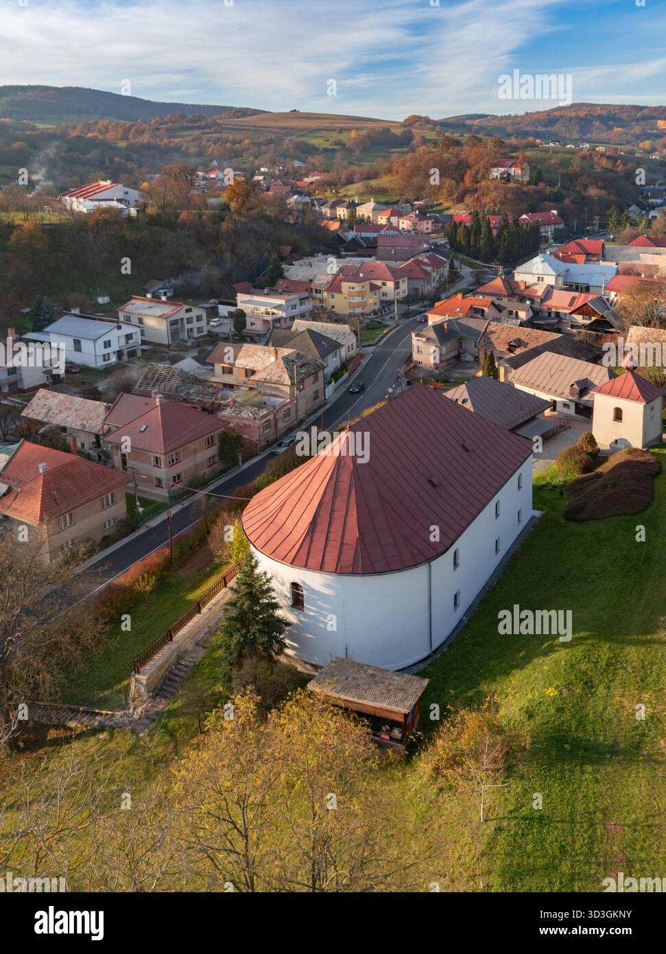 Vue aérienne de l'église évangélique avec son toit rouge et sa forme distinctive, nichée parmi les maisons et les collines, Horna Micina, Banskobystric Banque D'Images
