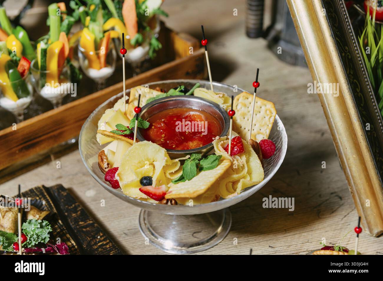 Nourriture, élégant bol de service rempli de boucles de fromage, craquelins, baies, noix et sauce chutney de tomate, idéal pour les événements ou les accords de vin Banque D'Images