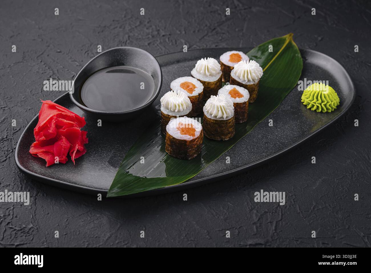 Nourriture, sushi avec fromage Philadelphie et saumon sur assiette asiatique noire Banque D'Images