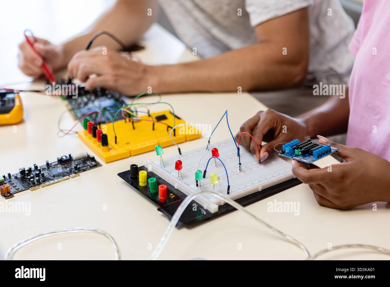 Étudiants travaillant avec des cartes de circuits électroniques et des microcontrôleurs en classe de sciences Banque D'Images