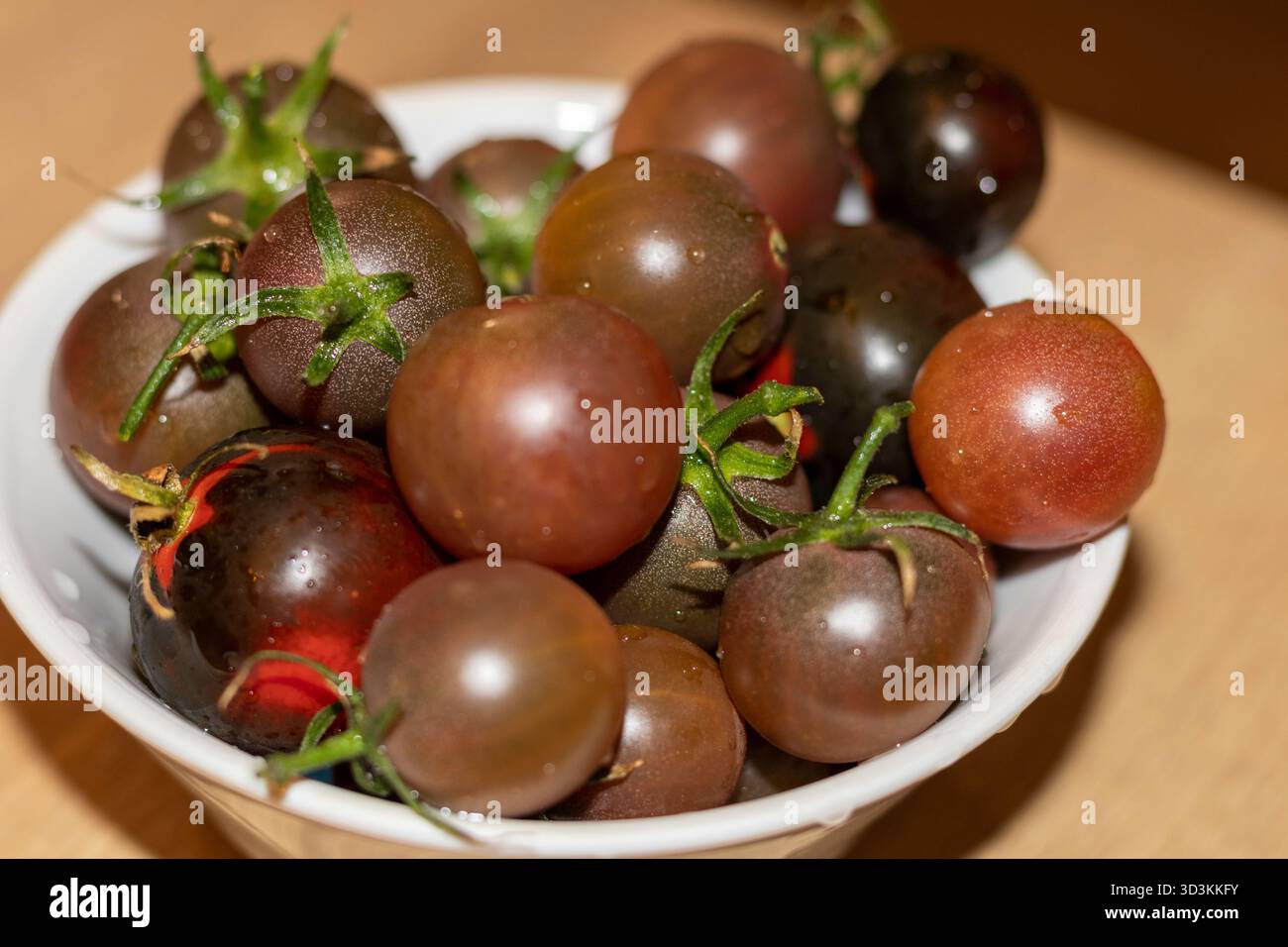 Tomates cerises foncées dans le bol Banque D'Images