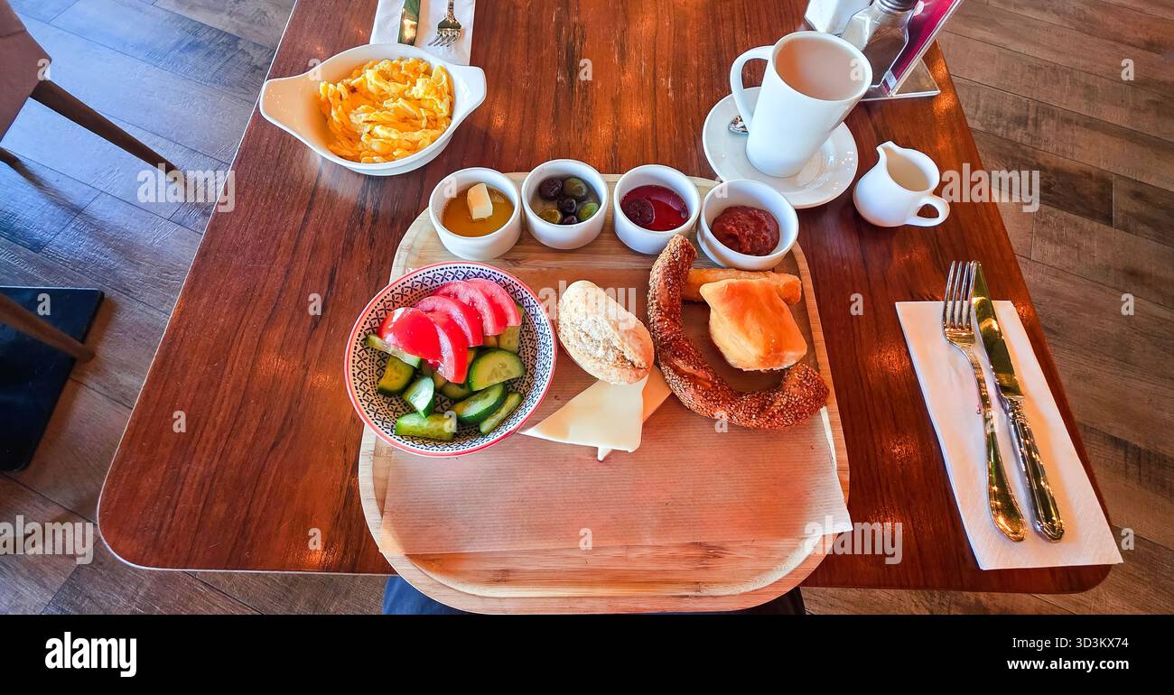 . Le petit-déjeuner se compose de fruits frais, de viennoiseries et de café servis sur une table en bois, créant une atmosphère chaleureuse et accueillante - Image de stock capturée avec un smartphone