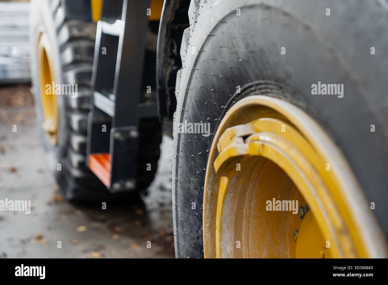 Vue rapprochée d'une roue de véhicule de construction lourde avec jante jaune et surface de pneu usée montrant les détails des machines industrielles et les conditions du chantier extérieur Banque D'Images