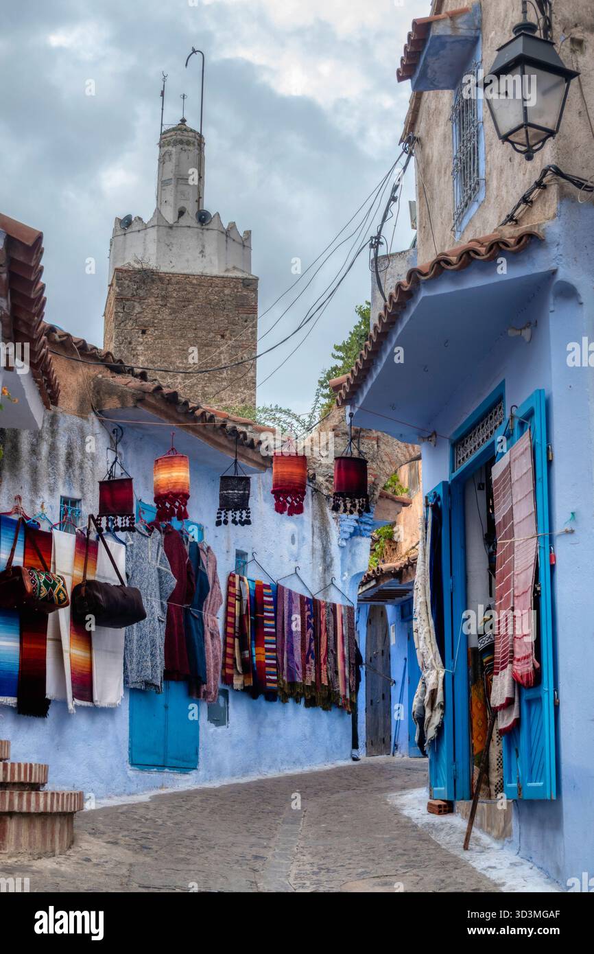Une ruelle escarpée, bleue et blanche à Chefchaouen, au Maroc, est fortement décorée. De nombreuses lanternes marocaines colorées pendent au-dessus de la tête, créant un et unique Banque D'Images