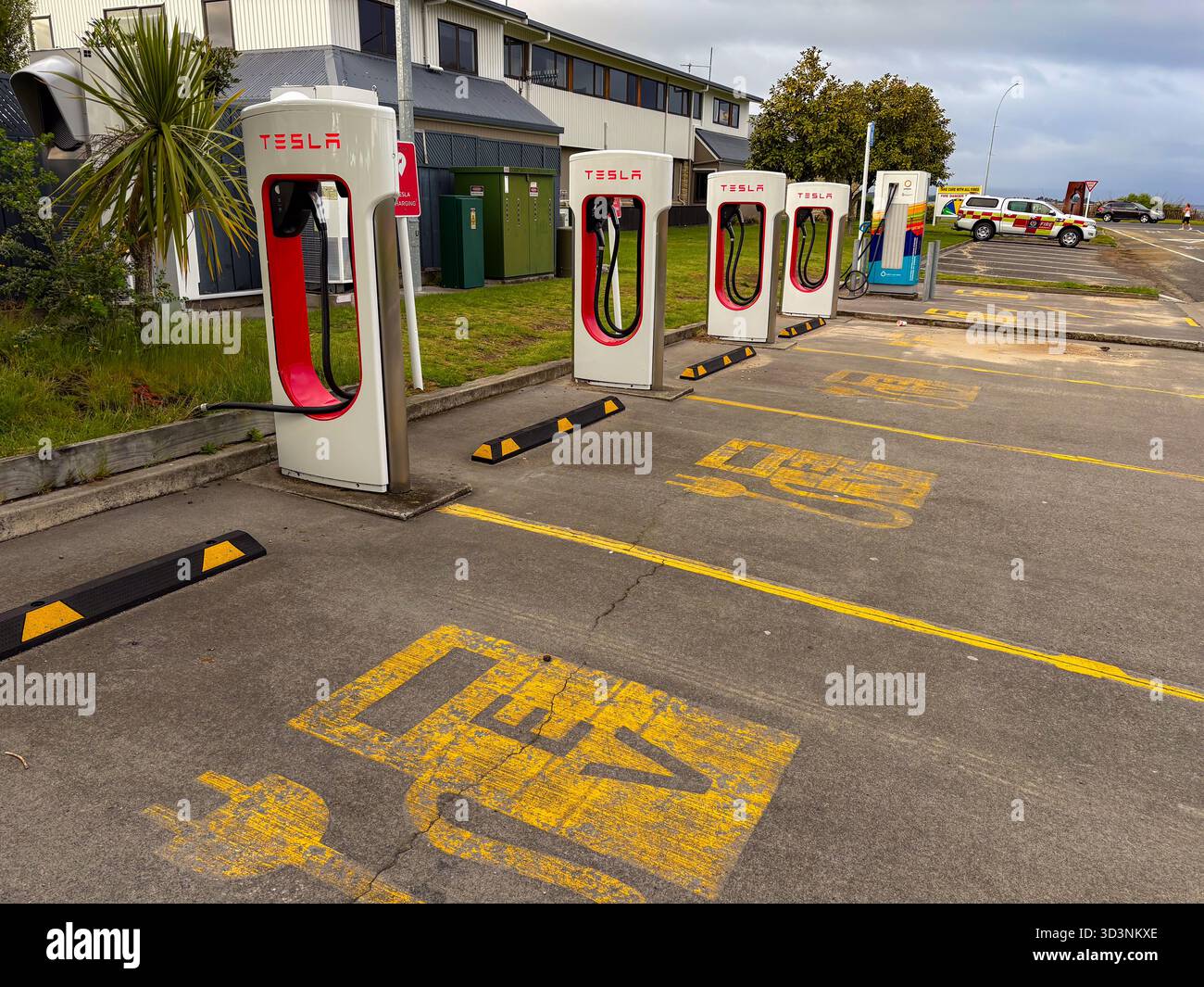 Station Tesla Supercharger avec plusieurs unités de recharge blanches et rouges pour véhicules électriques, avec symboles de stationnement EV sur l'asphalte à Taupo, Nouveau Banque D'Images