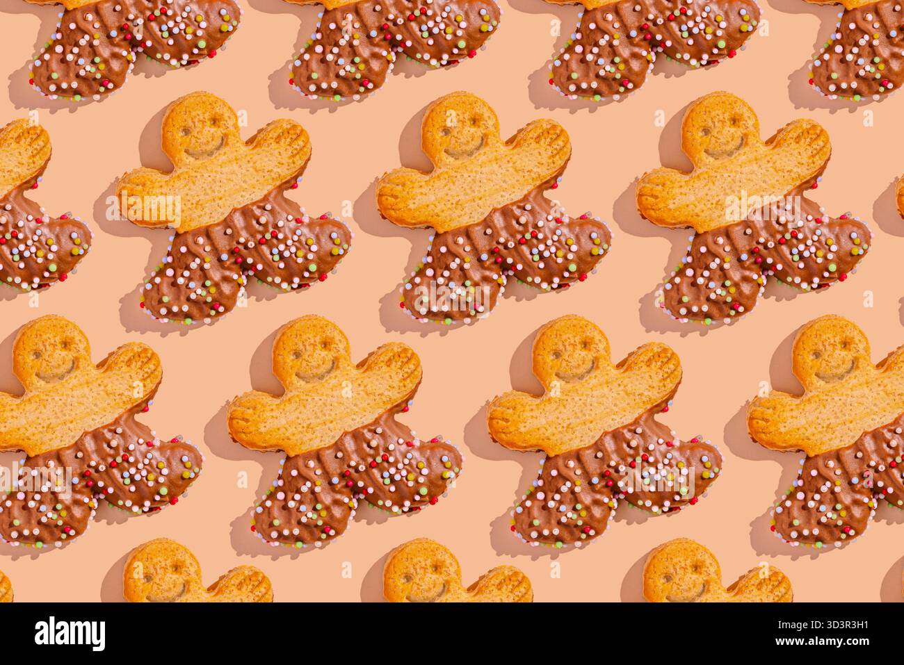 Un arrangement festif de biscuits hommes en pain d'épices, à moitié trempés dans le chocolat et ornés de saupoudres colorées, sur un fond beige doux, c Banque D'Images
