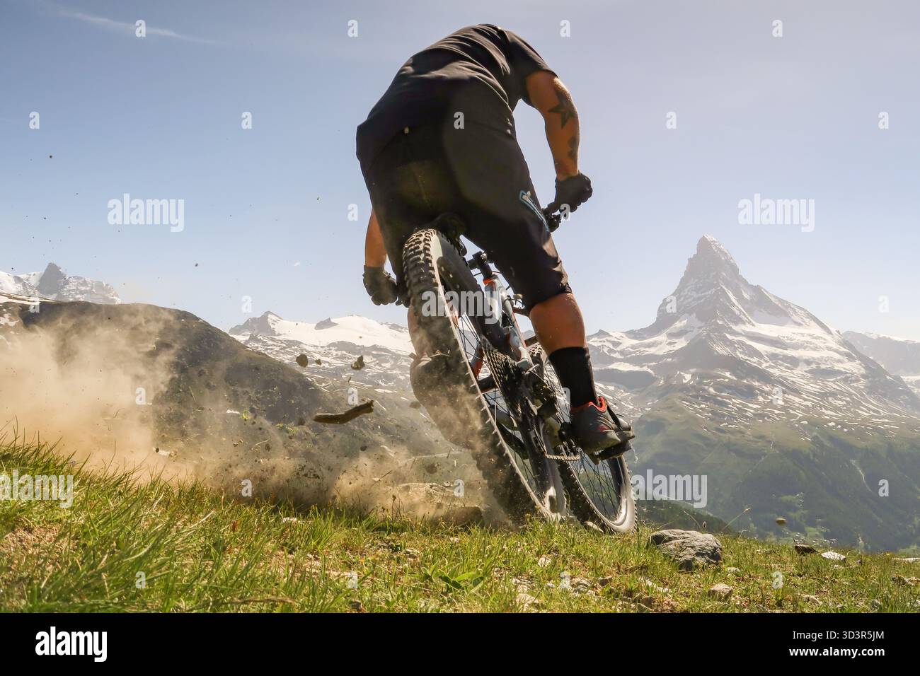Un VTT longe un sentier alpin luxuriant avec le Cervin en arrière-plan, capturant le frisson du vélo dans les paysages à couper le souffle Banque D'Images