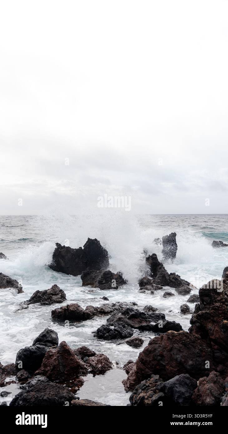 De puissantes vagues océaniques s'écrasent contre des roches volcaniques accidentées dans la zone de baignade de Negrito à Sao Mateus da Calheta, île de Terceira, Açores, Portugal, créant Banque D'Images