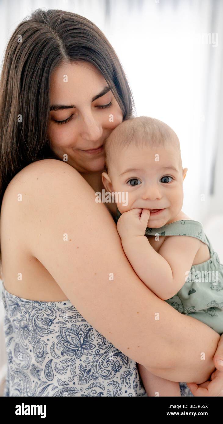 Une mère aimante tient doucement son bébé, créant un moment touchant de chaleur et d'affection familiale. Cette image capture magnifiquement le développement précoce et Banque D'Images