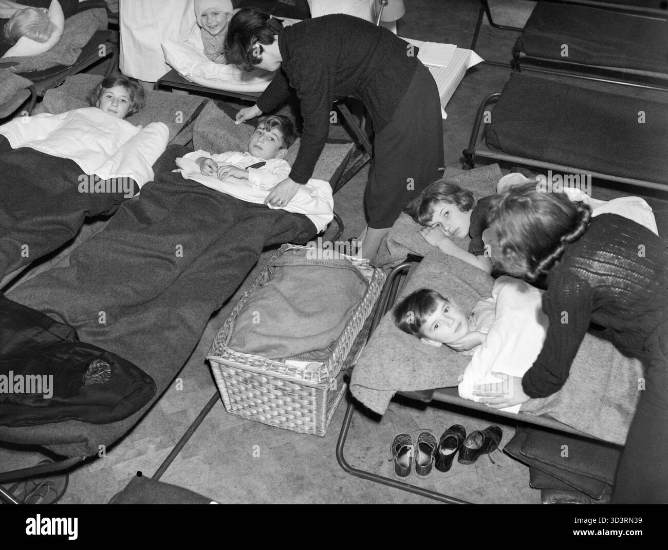 Sans-abri et les enfants orphelins s'installer pour dormir dans l'abri anti-aérien à l'Église John Keble, Mill Hill, Londres pendant le Blitz en 1940. Les sans-abri et/ou d'enfants orphelins s'installer à dormir sur des lits de camp dans l'abri anti-aérien à John Keble Église. Un panier au centre de la photo contient probablement un petit bébé, également sans abri par le Blitz. Banque D'Images