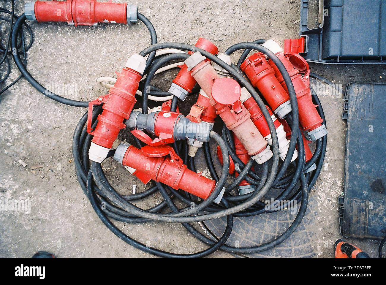 De nombreux connecteurs rouges à courant élevé et câbles enroulés sur un marché aux puces, texture analogique, affichage de composants industriels et électriques. Banque D'Images