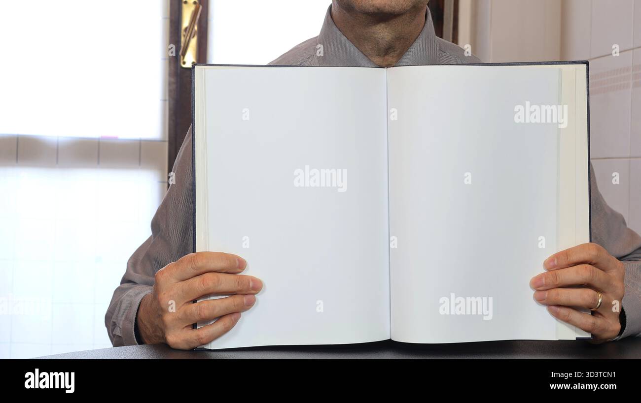 Un homme tient un livre avec des feuilles de papier vierges à la main. Le livre est devant lui. Banque D'Images