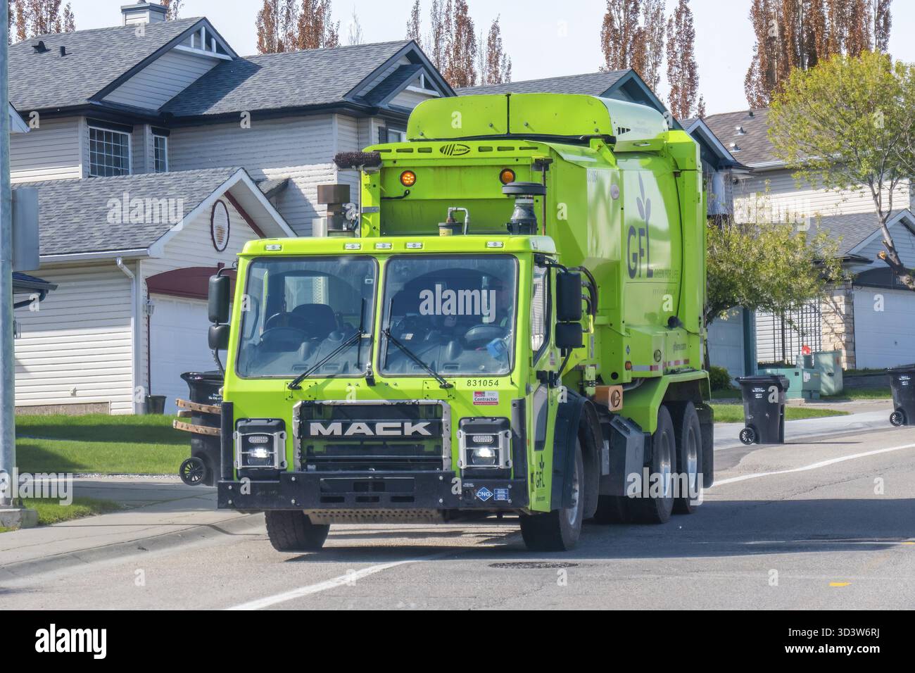 Calgary, Alberta, Canada. 5 juin 2025. Un camion à ordures écologiques GFL vert vif, arborant le logo Mack, opère dans une rue de banlieue, symboli Banque D'Images