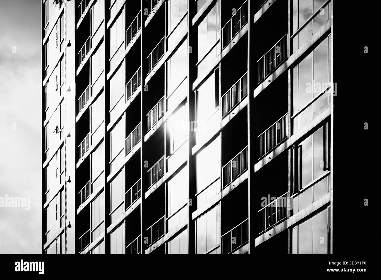 Abstraction artistique noire et blanche à contraste élevé de la façade de bâtiment en verre avec reflet blanc lumineux du soleil et du ciel Banque D'Images