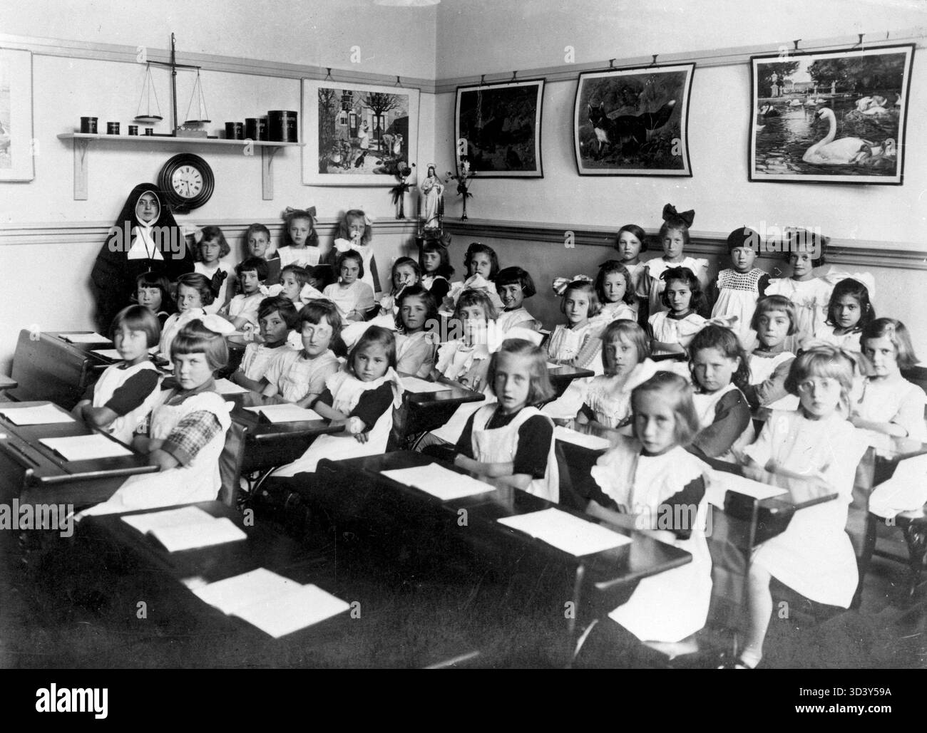 Photo de classe de troisième année à l'école catholique romaine de filles Joseph à Leyde, pays-Bas, 1927. Les élèves sont posés les bras croisés, avec le professeur, une religieuse, en arrière-plan et des affiches pédagogiques sur le mur. Banque D'Images