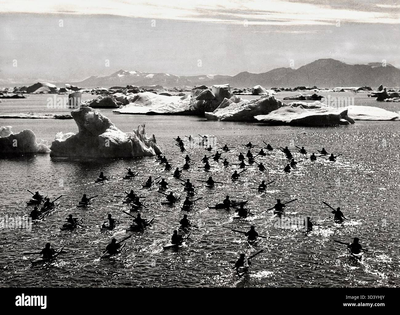 Image fixe du film de 1932 *S.O.S. Iceberg*, réalisé par Arnold Fanck. La scène montre des Inuits en kayak sur un iceberg, mettant en valeur leurs techniques traditionnelles de navigation arctique. Banque D'Images