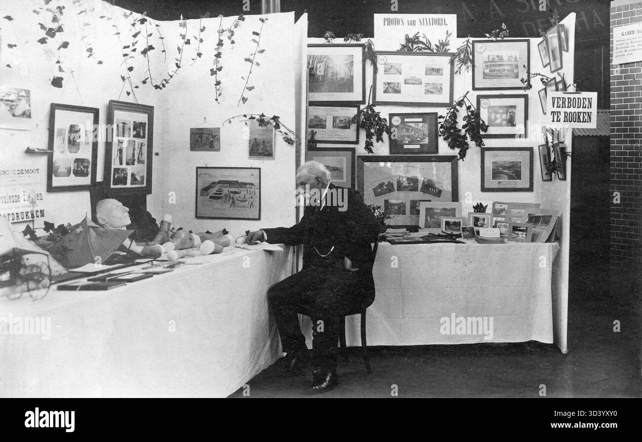 Un homme regarde des photographies de sanatoriums et d'articles utilisés dans le traitement de la tuberculose à la Haye, pays-Bas, 1911. Banque D'Images