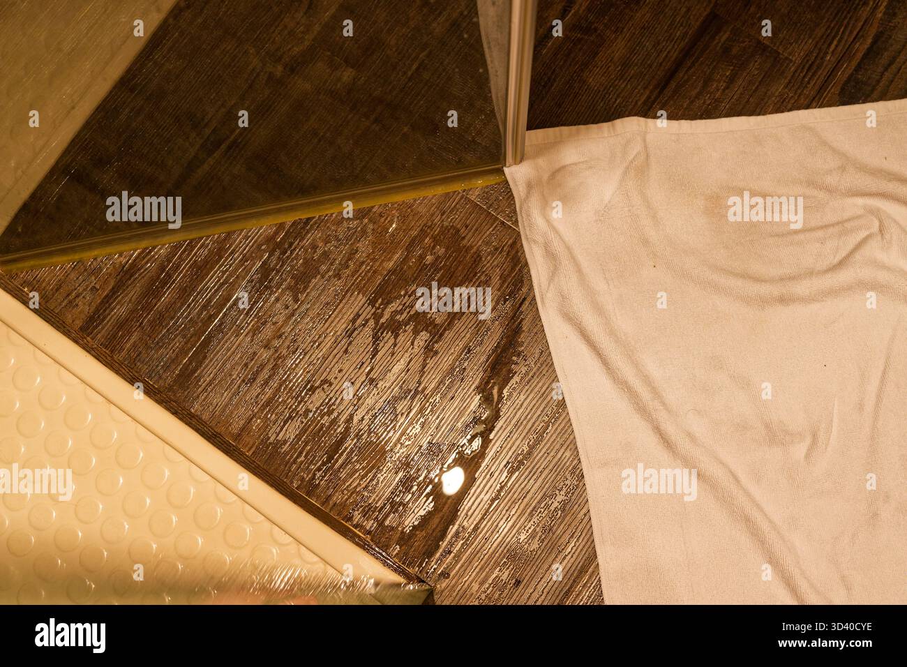 L'eau scintille à travers la base de douche et une serviette blanche pliée repose sur la surface humide, les reflets doux montrent une utilisation récente et le coin calme se sent bien Banque D'Images