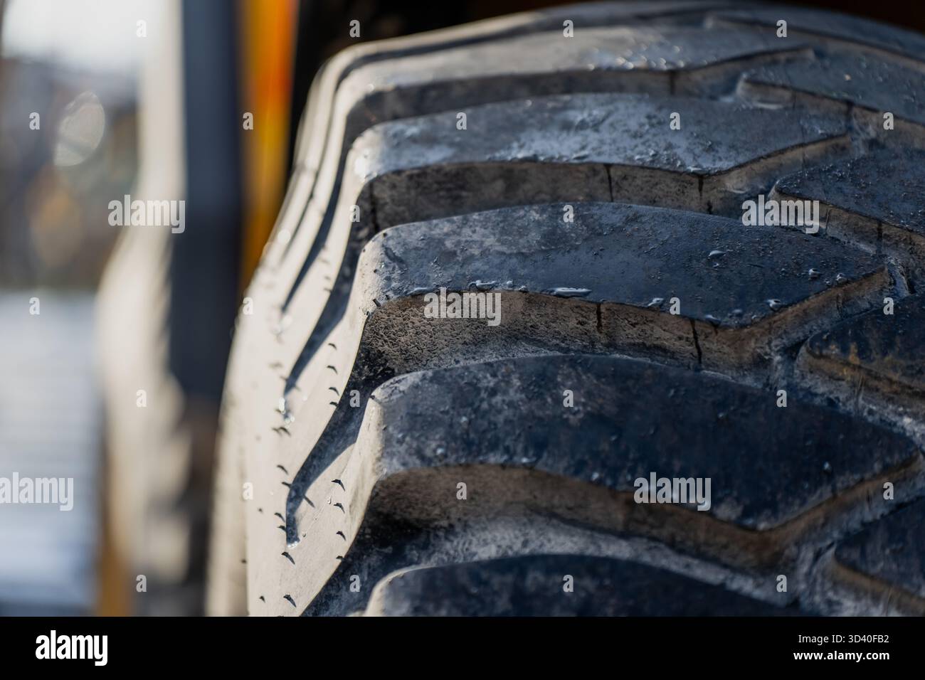 Gros plan de la bande de roulement d'un pneu d'équipement lourd avec usure visible et texture de saleté montrant le motif de traction d'un véhicule de construction, la surface en caoutchouc industriel Banque D'Images