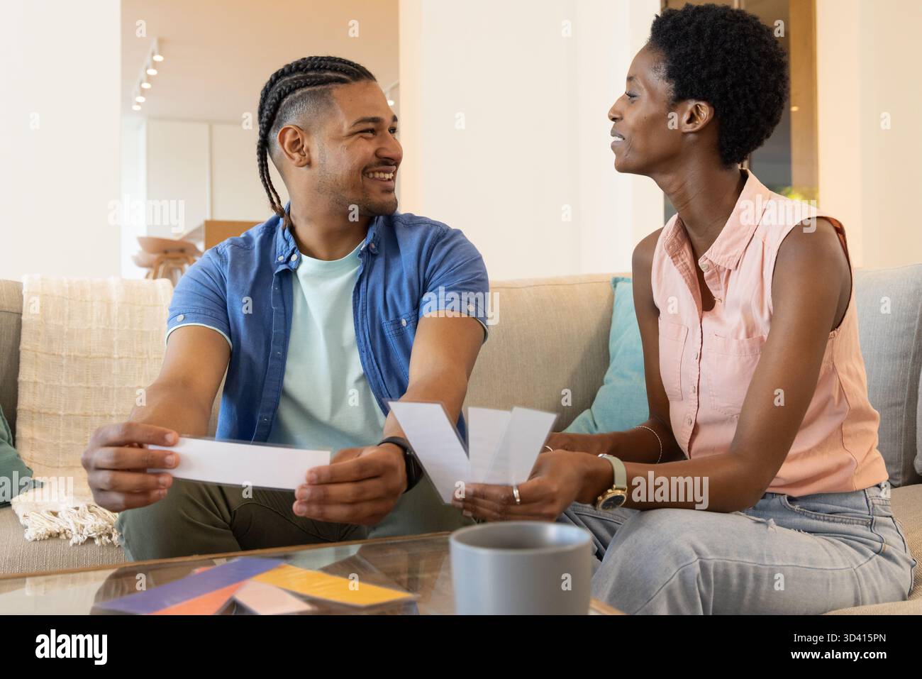 Choisir des échantillons de peinture divers couple assis sur le canapé dans le salon, avec tasse à café Banque D'Images