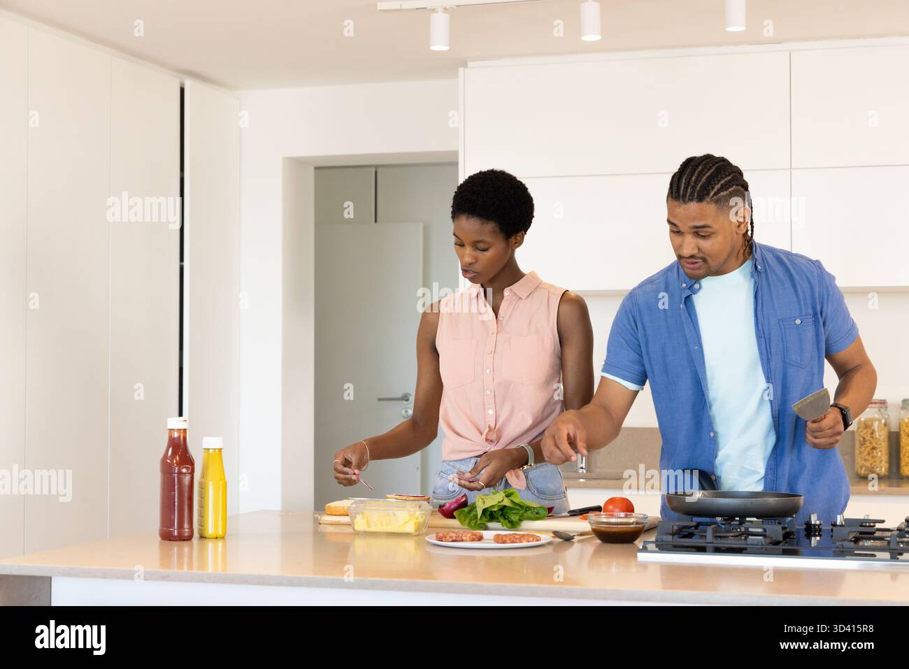 Divers couples de légumes de cuisson dans la cuisine moderne, avec spatule de planche à découper et table de cuisson à gaz Banque D'Images
