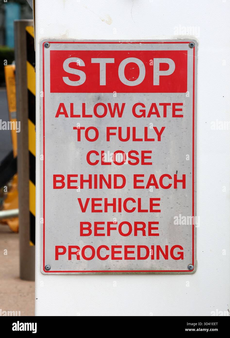 Arrêt - laissez la porte se fermer complètement derrière chaque véhicule avant de poursuivre le panneau fixé à un poteau blanc Banque D'Images