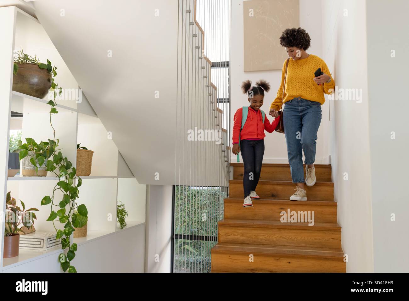 Descendant escaliers divers mère et fille tenant la main avec le téléphone sac à dos à la maison, espace de copie Banque D'Images