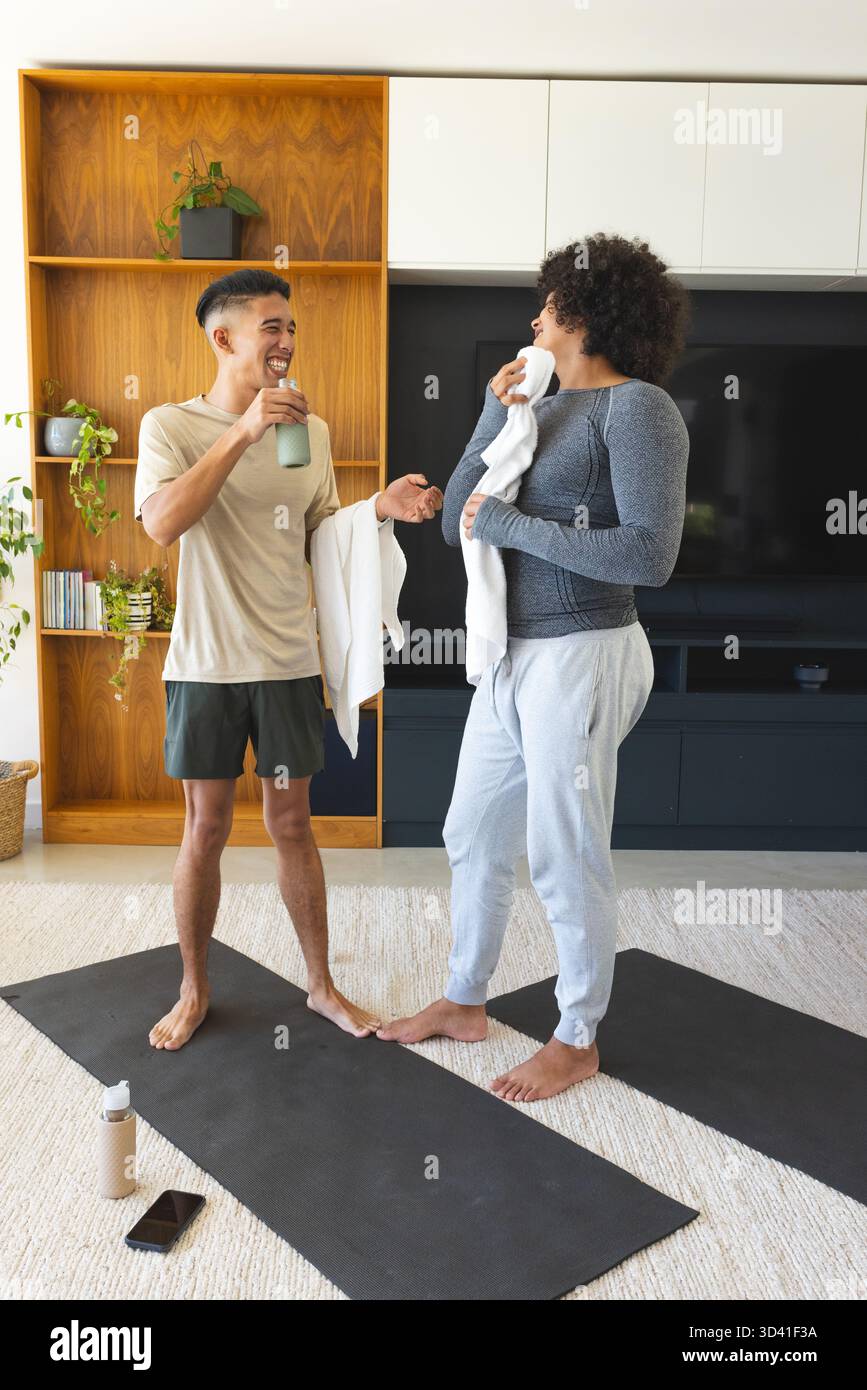 Bavarder divers amis masculins debout sur des tapis dans le salon, avec des serviettes et des bouteilles d'eau Banque D'Images