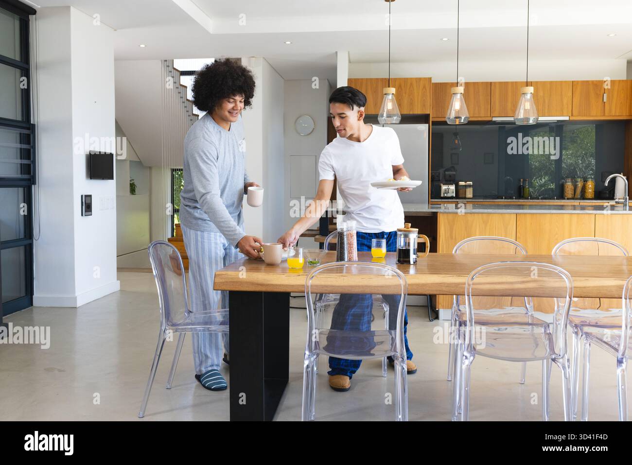 Rire divers amis masculins debout à la table de cuisine ouverte, avec des tasses et des assiettes de petit déjeuner Banque D'Images