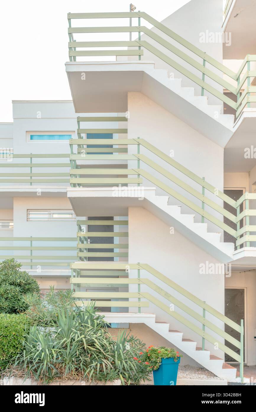 Escalier extérieur d'un immeuble d'appartements blanc moderne avec balustrades vert pastel et jardin au premier plan Banque D'Images