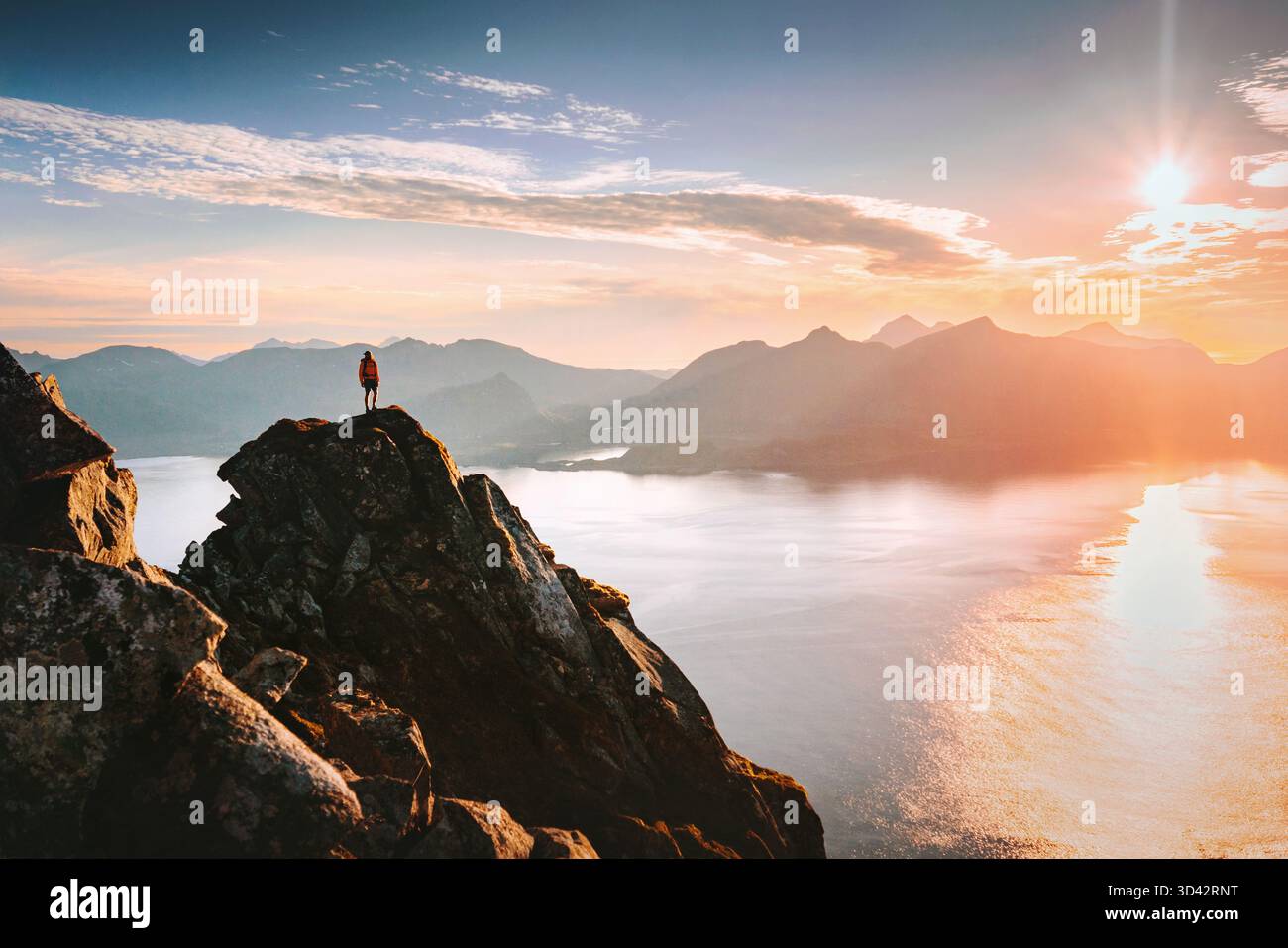 Homme voyage en Norvège escalade des montagnes profitant du coucher du soleil vue sur la mer aérienne dans les îles Lofoten, aventure randonnée pédestre d'été vacances actives en plein air gratuit Banque D'Images