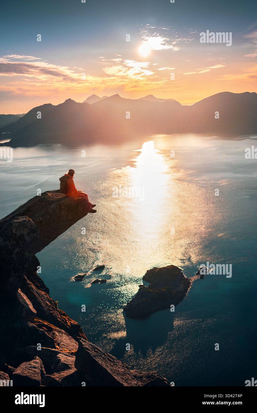 Homme touriste randonnée en Norvège assis sur le bord de la falaise Torsketunga vue aérienne sur la mer voyage dans les îles Lofoten grimpant des montagnes rocheuses seul, aventure épique Banque D'Images