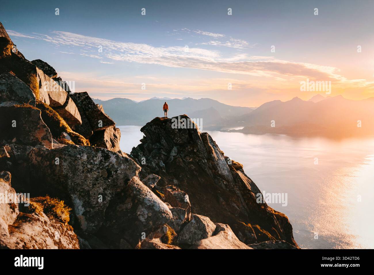 Homme grimpant les montagnes en Norvège debout sur la roche falaise au-dessus de la mer voyage solo dans les îles Lofoten, aventure randonnée voyage d'été vacances extrêmes outdo Banque D'Images
