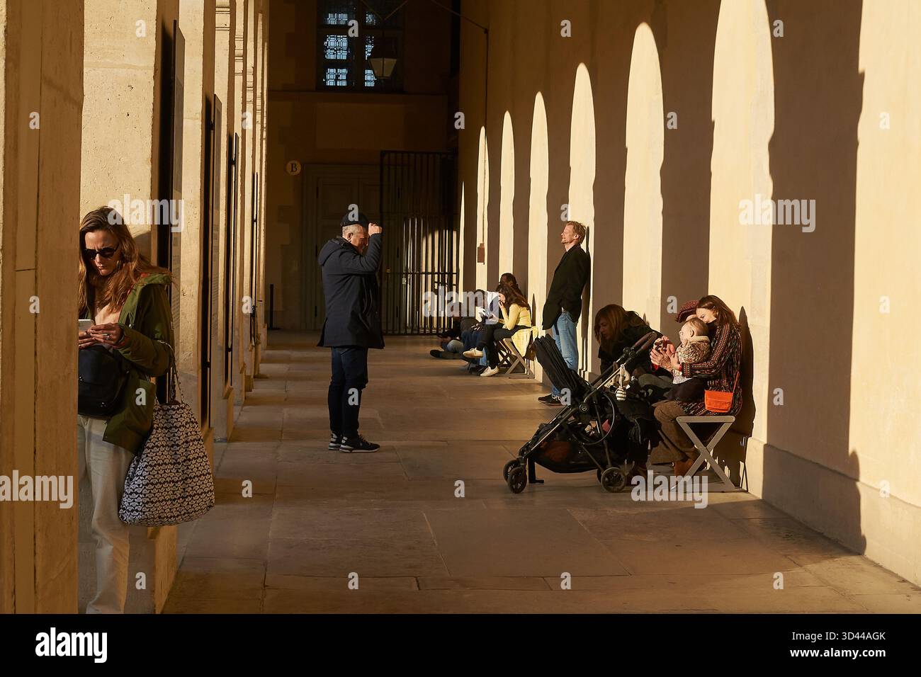 Les gens profitent d'une journée ensoleillée dans une rue parisienne avec des ombres et des arches, Hôtel des Invalides, Paris, France Banque D'Images