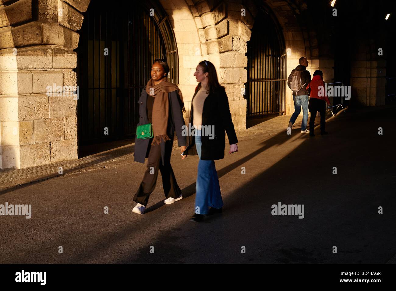 Deux femmes marchant dans une rue de Paris dans la lumière du soir sous une arche, Pont Alexandre III, Paris, France Banque D'Images