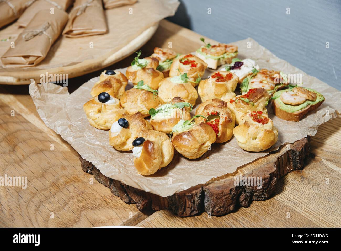 Nourriture, sélection de pâtisseries salées, canapés et crostini avec des garnitures comme la crème, les crevettes et le caviar servis sur un plateau en bois Banque D'Images