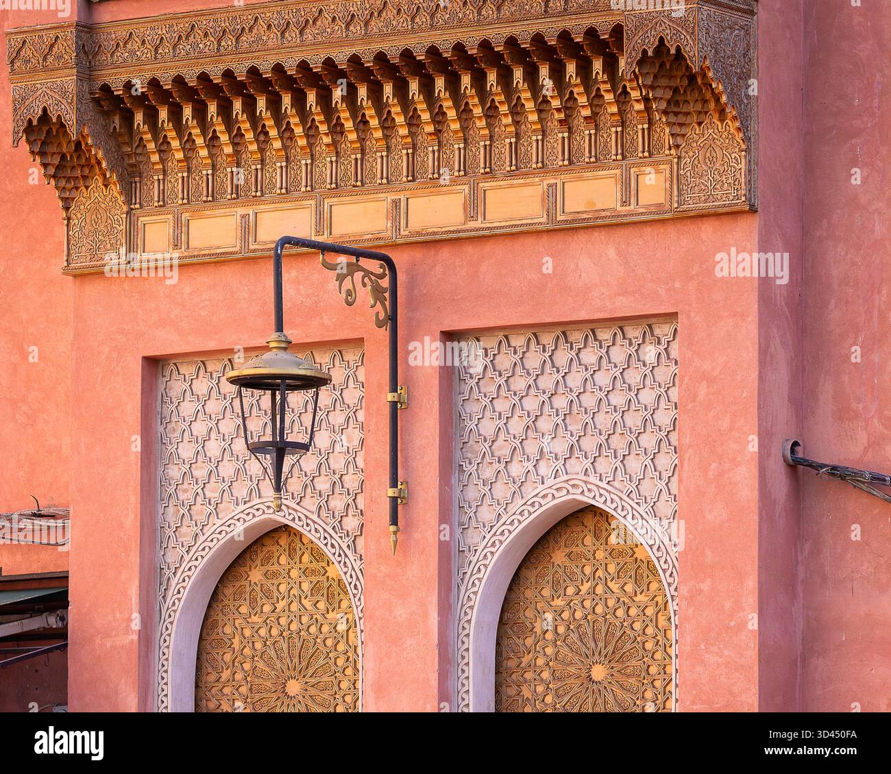 Architecture marocaine dans la médina de Marrakech, avec des portes voûtées sculptées, des motifs géométriques islamiques et une lanterne sous des détails en bois ornés. Banque D'Images
