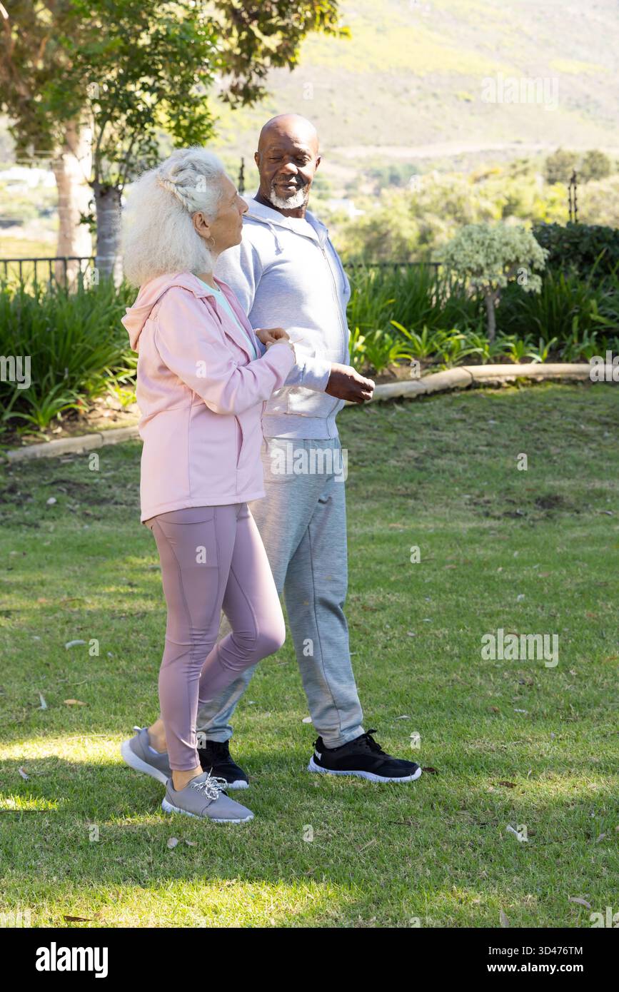 Marchant divers couples seniors discutant sur la pelouse herbeuse dans le jardin de l'arrière-cour, partageant une promenade paisible Banque D'Images