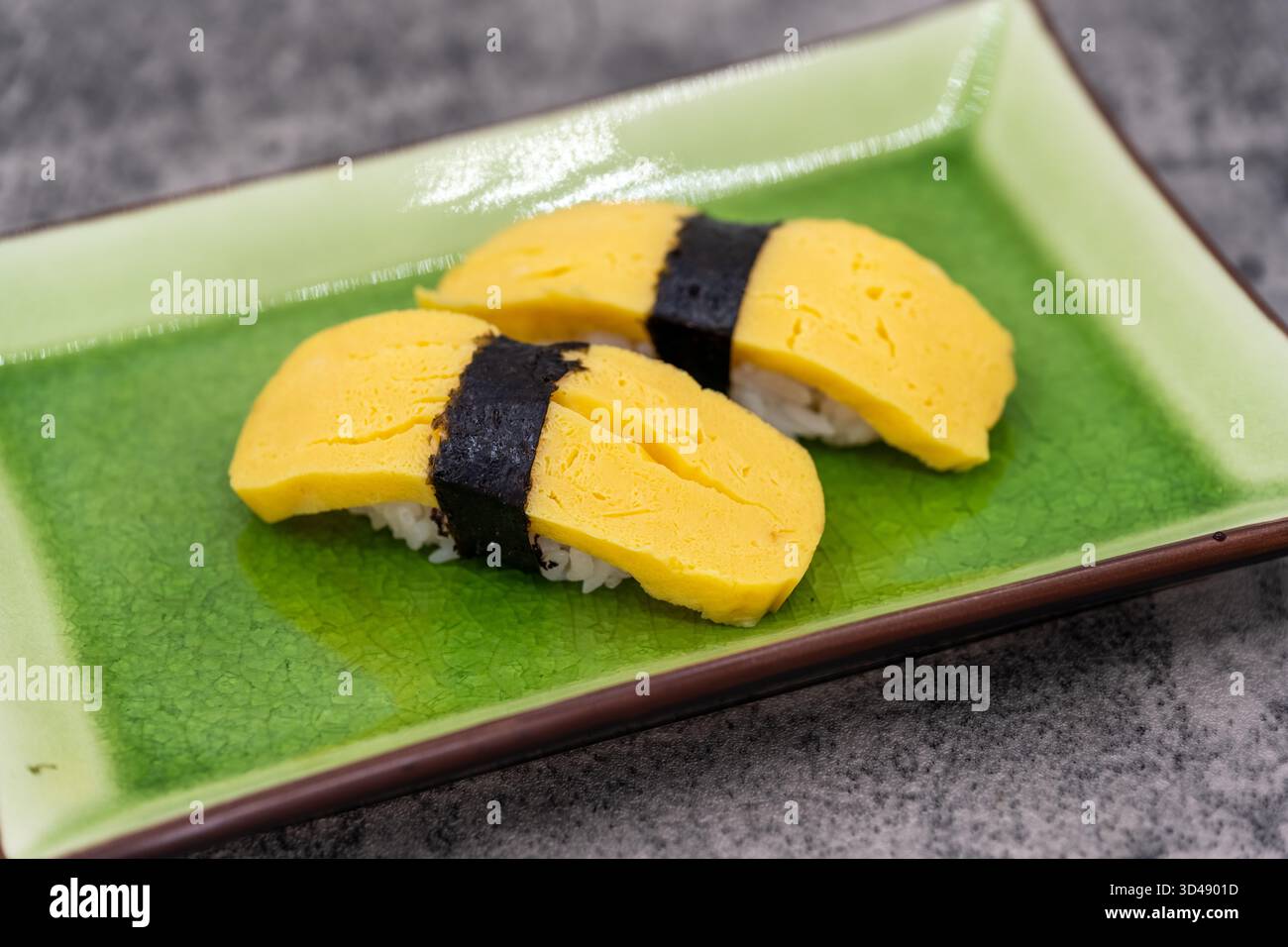 Assiette de sushi avec une paire de nigiri aux œufs comme apéritif pour un repas asiatique. Banque D'Images