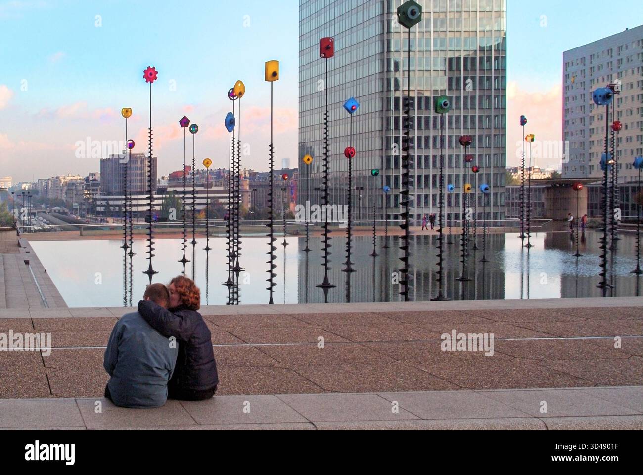 Scène d'archives prise l'année 2003 à Paris un gratte-ciel de grande hauteur également avec vue arrière de l'homme ami inconnu et un couple de femmes assis seul à côté du bassin de Takis presque déserté et paisible cette œuvre d'art lumineuse signaux conçue par grec artiste Panayiotis Vassilakis le couple peut-être en regardant la fonction d'éclairage sur le dessus des poteaux plantés dans le calme et peu profond L'eau et les lumières sur les poteaux prennent vie à l'approche du crépuscule au-dessus du parc d'activités de la Défense dans le département des hauts-de-Seine à Paris France eu Banque D'Images