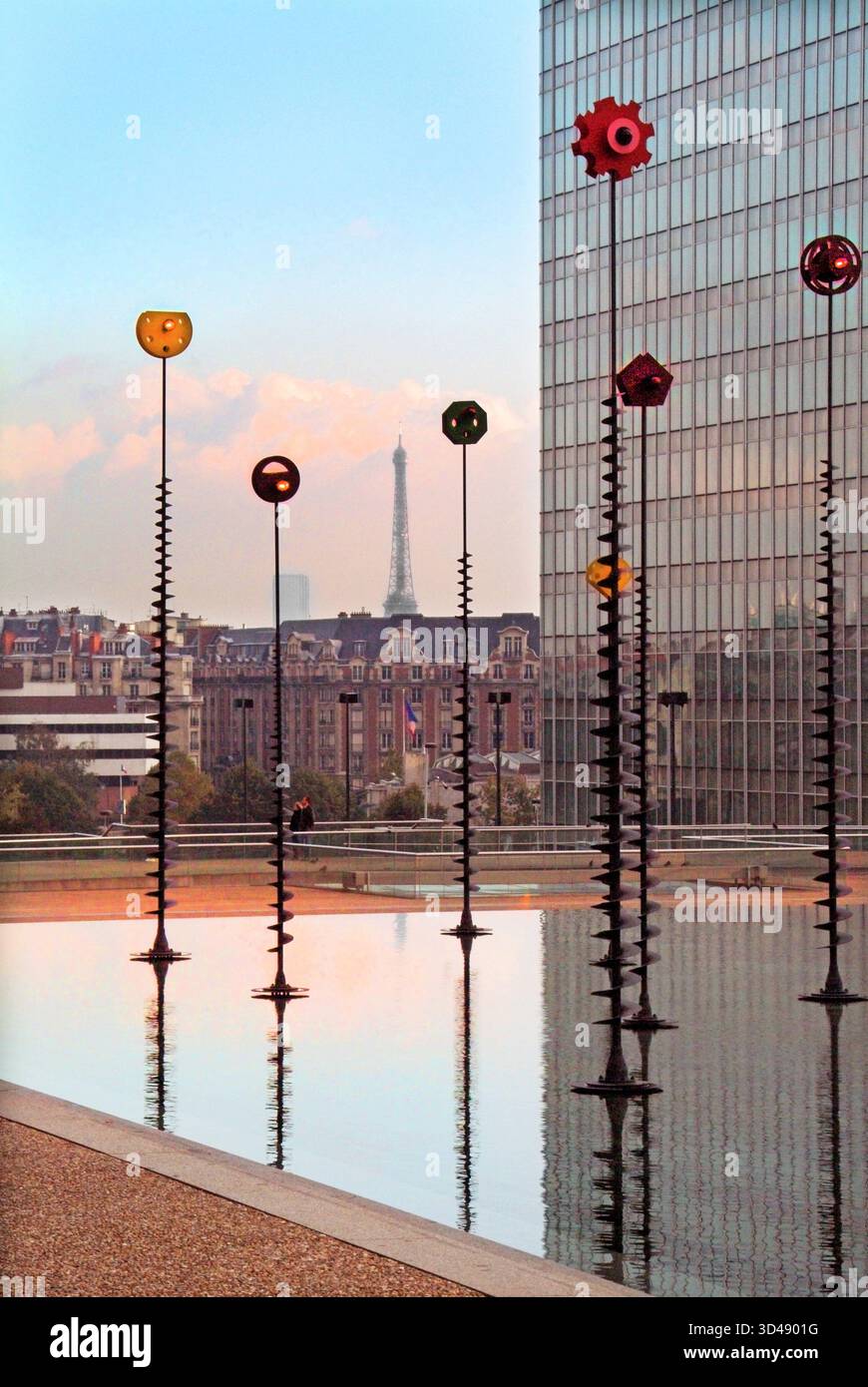 Archive scène de paysage urbain prise en l'an 2003 à Paris une vue d'une partie du paisible bassin Takis presque déserté piscine d'eau et une œuvre d'art lumineux signaux ont tous été conçus par l'artiste grec Panayiotis Vassilakis ici un éclairage rapproché arrangement sur le dessus des poteaux flexibles plantés dans cette caractéristique d'eau calme et tranquille qui prend vie à mesure que le crépuscule descend sur un immeuble gratte-ciel de bureaux dans le Parc d'affaires de la Défense dans le département des hauts-de-Seine de Paris avec un contour lointain de la célèbre Tour Eiffel en France eu Banque D'Images