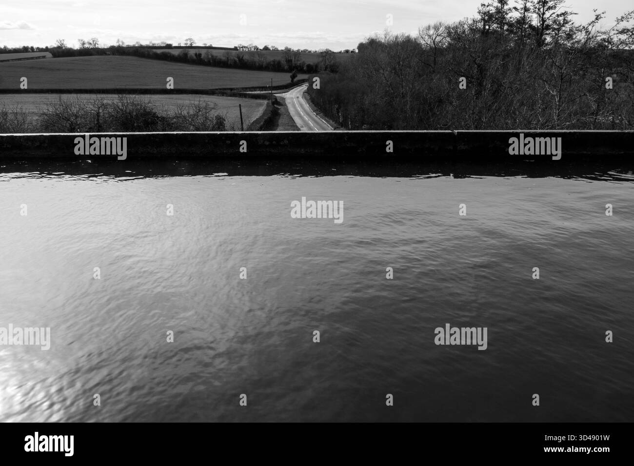 Vue en noir et blanc depuis l'aqueduc d'Edstone sur le canal Stratford-upon-Avon, regardant de l'autre côté du canal vers la route rurale sinueuse Banque D'Images