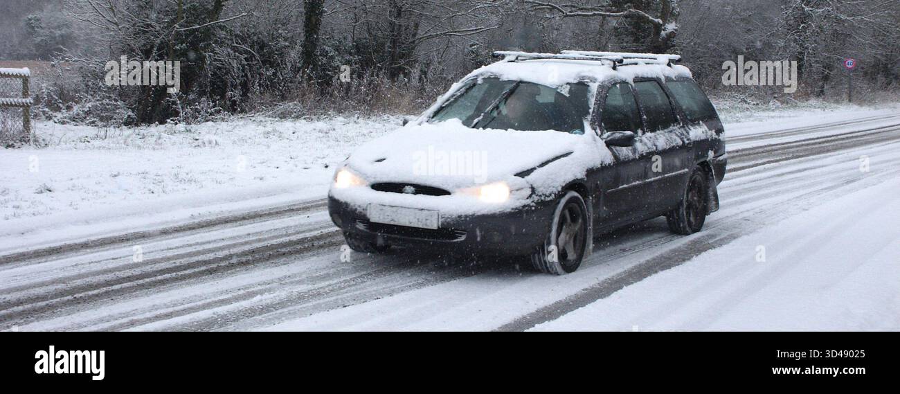 Archive Close up view en année 2003 scène de paysage de temps froid d'hiver avec capot de voiture et toit couvert de neige conduisant le long de la route de village glacée rurale non traitée après une récente chute de neige dans la périphérie de la campagne de village de Doddinghurst conduisant vers Brentwood une ville dans l'Essex Angleterre Royaume-Uni Banque D'Images
